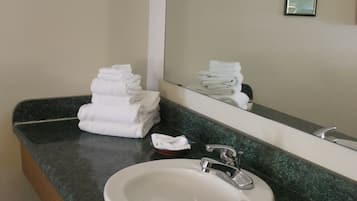 A bathroom with a sink, mirror, and stacked towels.