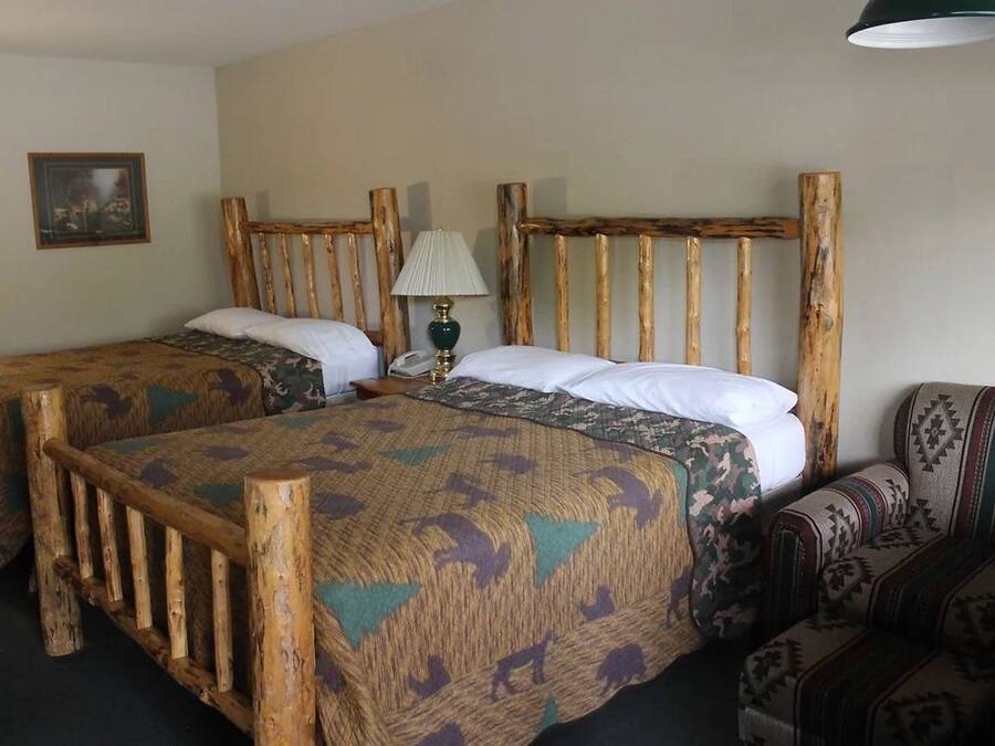 A room with two wooden beds, a patterned sofa, a lamp, and a framed picture on the wall.