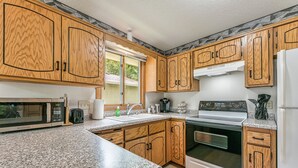 Una cucina con mobili in legno, un forno a microonde, un piano cottura e un frigorifero.