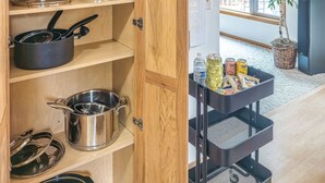 Una cucina con mobili in legno, una macchina da caffè, pentole, padelle e un altoparlante nero.