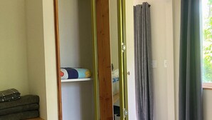 Une pièce comprenant une armoire, un lit, un panier et une fenêtre avec des rideaux.