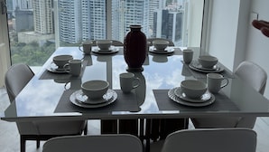 Comedor con mesa para seis, un centro de mesa en un florero y vista a la ciudad a través de amplias ventanas.