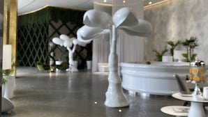 Un vestíbulo moderno con piso de mármol, un mostrador de recepción y esculturas blancas decorativas.