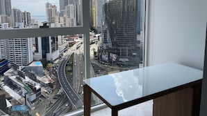 Un paisaje urbano a través de una ventana que muestra rascacielos, una autopista y un hotel llamado 'Hotel Las Americas Golden Tower'.