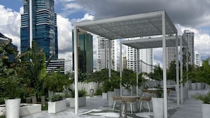 Terraza en la azotea con pérgola, mobiliario y plantas en macetas.