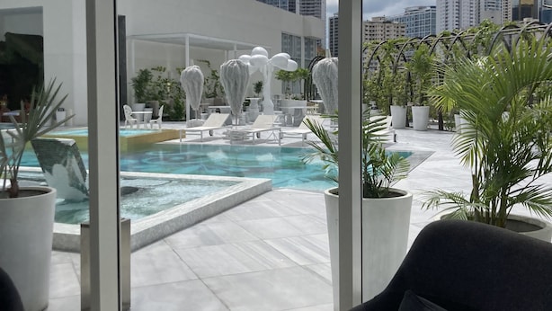 Un área de piscina en la azotea con sillones de descanso y plantas en macetas.