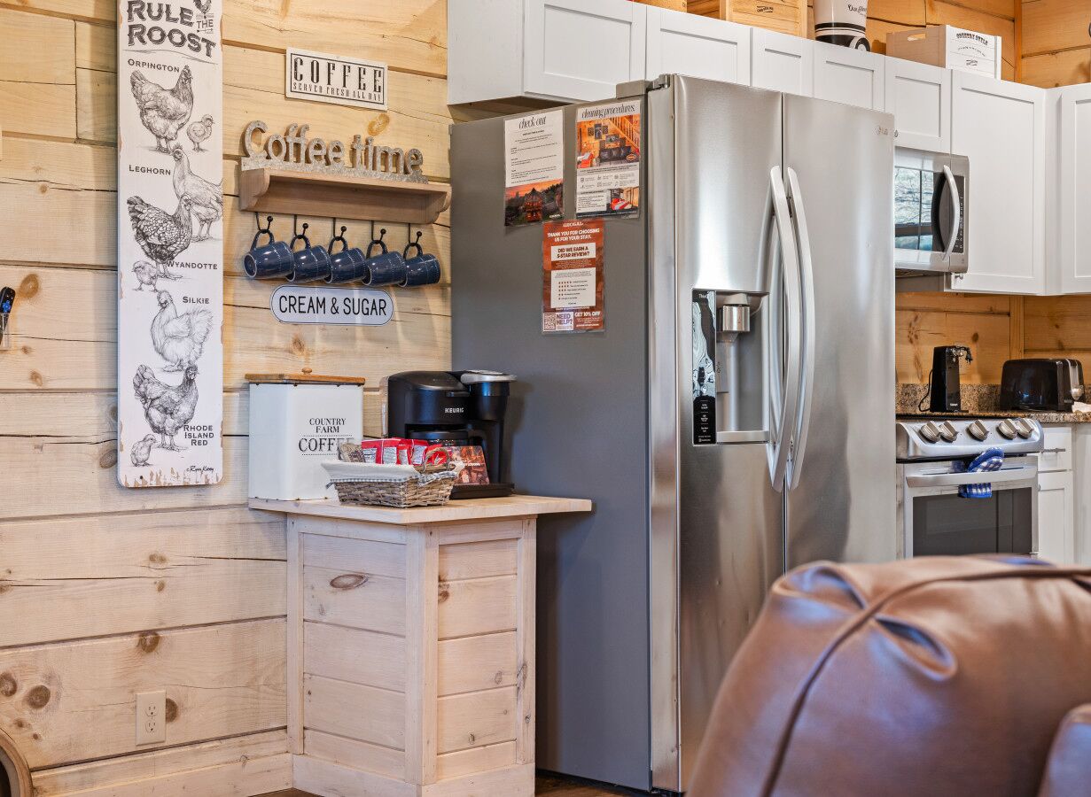Una cocina con un refrigerador de acero inoxidable, una cafetera y un letrero que dice 'café' en la pared.