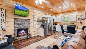 Ein gemütliches Blockhaus-Interieur mit Kamin, Fernseher, Küchenzeile und einem Wohnzimmer mit einer Ledersofa.