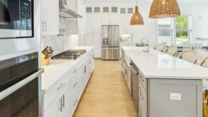 A modern kitchen with white cabinetry, stainless steel appliances, and a large island. - Vitamin Sea by Stay on 30a (Inlet Beach)