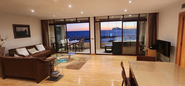 Un salon spacieux doté d’une grande porte vitrée donnant sur un balcon avec vue sur la mer.