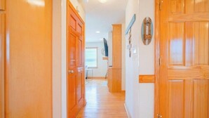 A hallway with wooden doors and a view into a room with a window and blinds. - Beachside Breeze! 5 BR 3 BA beach paradise!  (Nags Head)