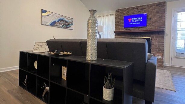 Ein modernes Wohnzimmer mit einer schwarzen Unterhaltungsanlage, einem Deckenventilator, einem Flachbildfernseher und einem Kamin aus Ziegelsteinen.
