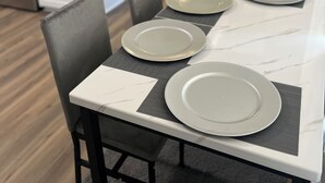 Ein Essbereich mit einem für vier Personen gedecktem Tisch, komplett mit Tellern und Servietten.