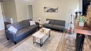 Ein modernes Wohnzimmer mit einer Eckcouch, einem weißen Couchtisch und einem Kamin.
