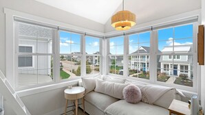 A modern room with a white sofa, a small round table, and a hanging light fixture. - Sit, Stay, Relax | Welcome to Serendipity (Ottawa)