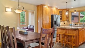 A kitchen with wooden cabinets, a central island with stools, and a dining table with chairs. - Mountain Retreat with Deck and Hot Tub (Blue River)