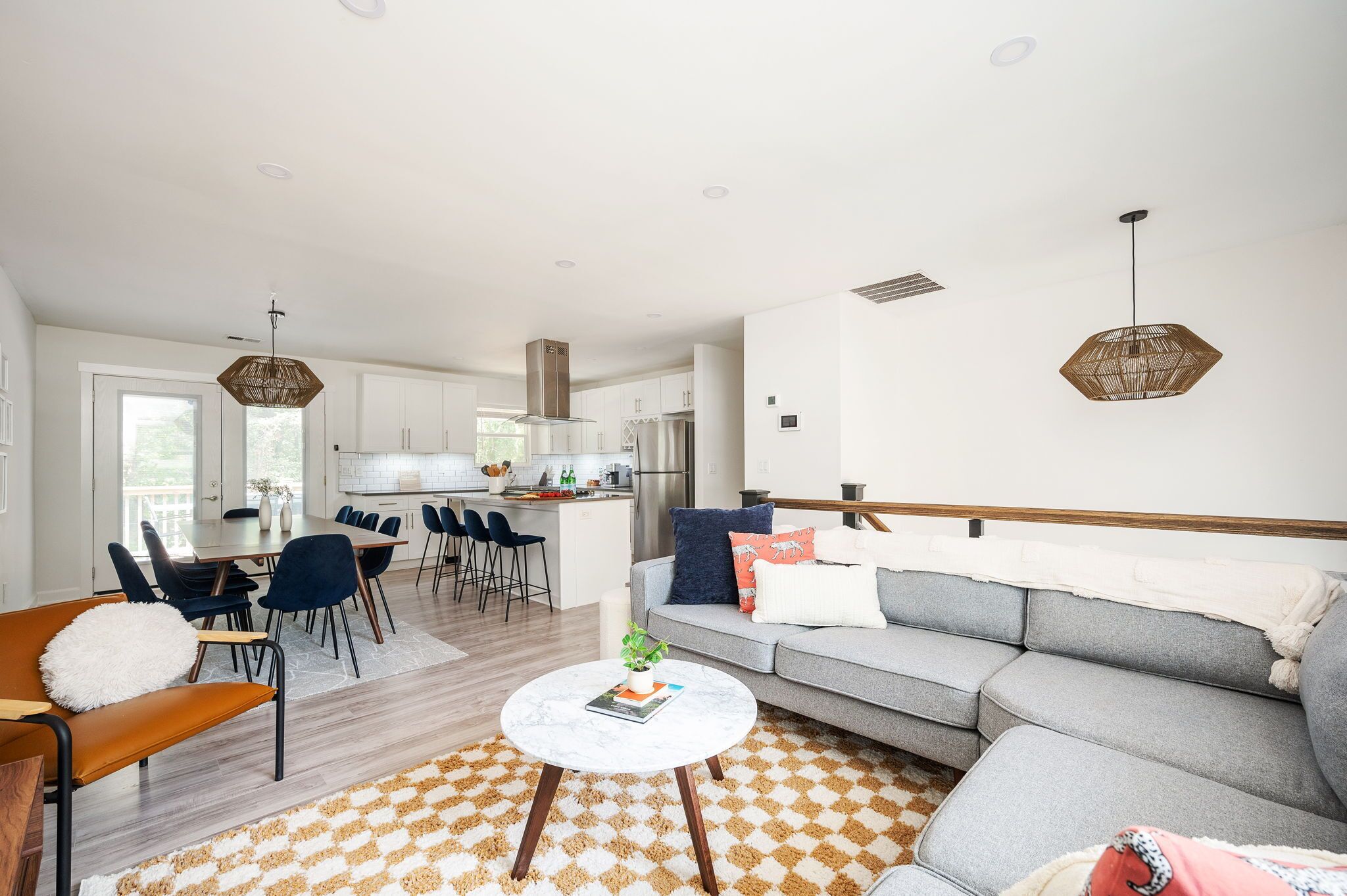 Un salon moderne avec un canapé gris, une table basse ronde et un coin repas comprenant une table et des chaises blanches.