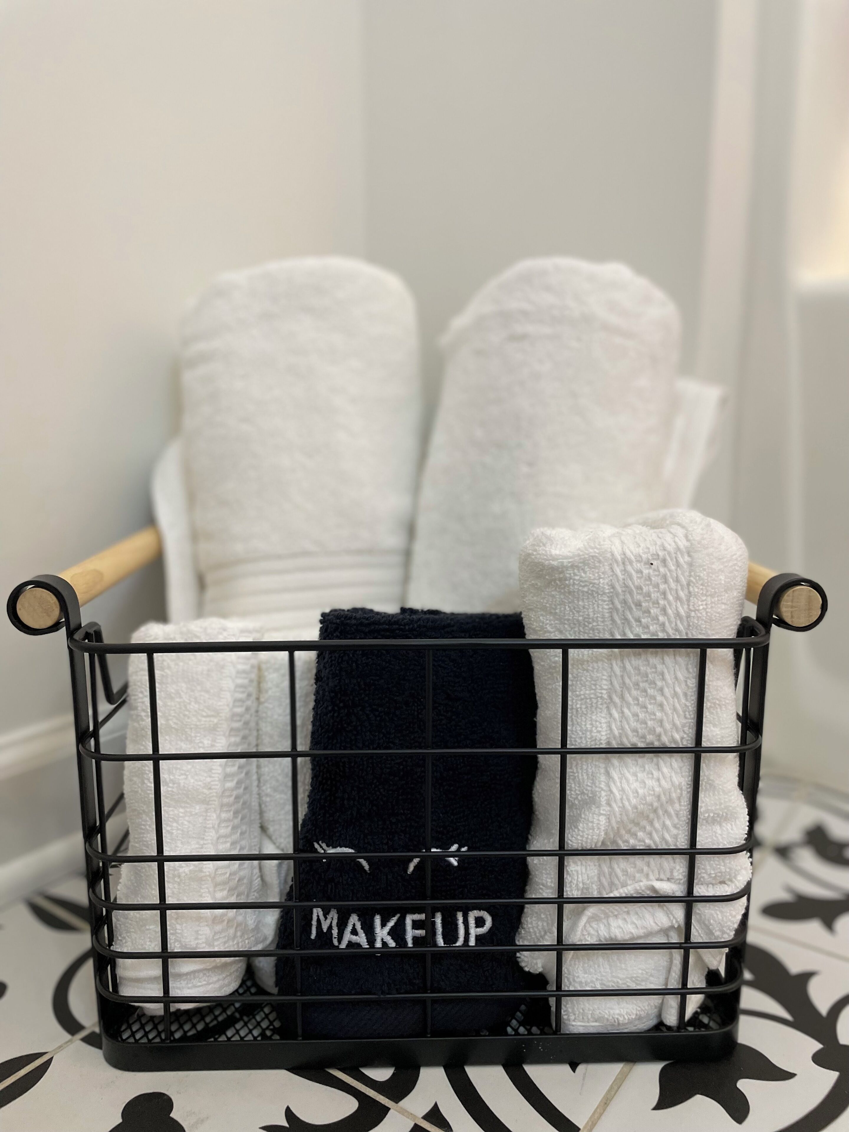 A black metal rack with white and black towels labeled "MAKEUP".