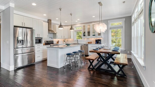 A modern kitchen with stainless steel appliances, white cabinetry, and a central island with bar stools.