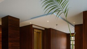 A modern lobby with a central staircase, wooden paneling, and a large potted plant. - Luxury Seaside Stay – Your Dream Vacation Awaits! (Port Said Governorate)