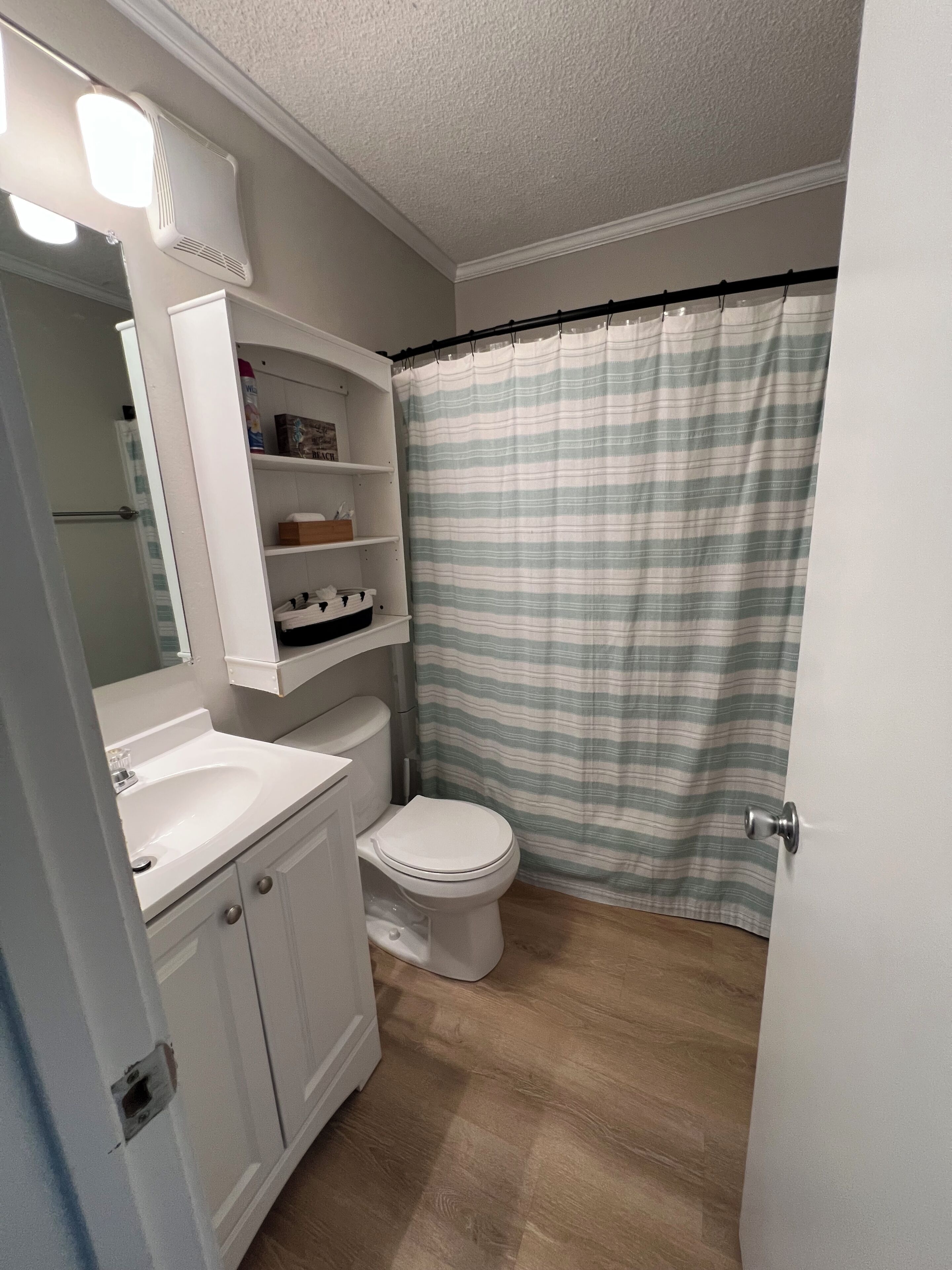Ein Badezimmer mit Toilette, Waschbecken, Spiegel und Regalen.
