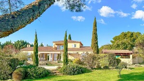 A two-story house with a tiled roof, surrounded by a well-maintained lawn and tall cypress trees. - Beautiful villa with pool close to Mont-Ventoux (La Roque-sur-Pernes)