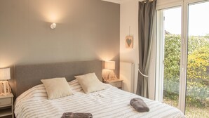 A bedroom with a bed, bedside lamps, a nightstand, a window with curtains, and a view of greenery outside. - Beautiful villa with pool close to Mont-Ventoux (La Roque-sur-Pernes)