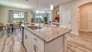 Eine moderne Küche mit Granit-Arbeitsplatten, eine Essecke mit Tisch und Stühlen sowie ein Blick ins Freie.