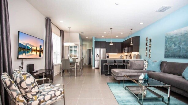 A modern living room with a sofa, coffee table, and a TV mounted on the wall. - Serene Villa with Private Pool (Clermont)