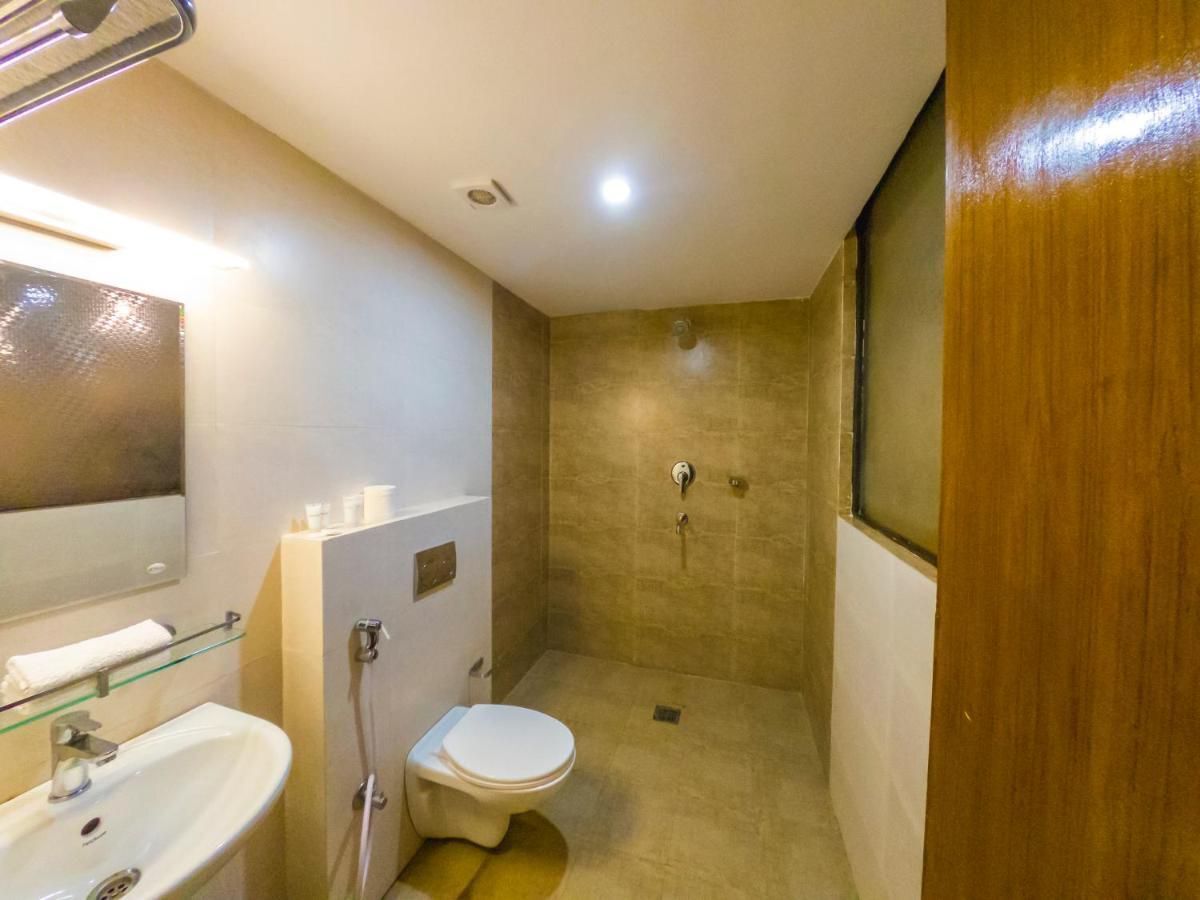 Un baño pequeño y funcional con cabina de ducha de vidrio, un lavamanos blanco y un inodoro.