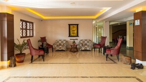 A lobby with a polished marble floor, red upholstered chairs, a patterned sofa, and a framed menu on the wall. - Hotel Ananda Pashupati  (Kathmandu)
