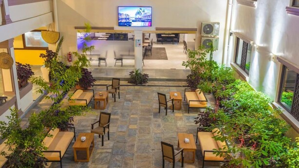 A spacious indoor area with multiple seating arrangements, a central reception desk, and a television screen. - Hotel Ananda Pashupati  (Kathmandu)