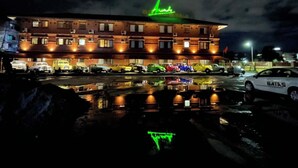 A hotel with multiple floors, a neon sign on the roof, and a parking lot with several cars. - Hotel Ananda Pashupati  (Kathmandu)