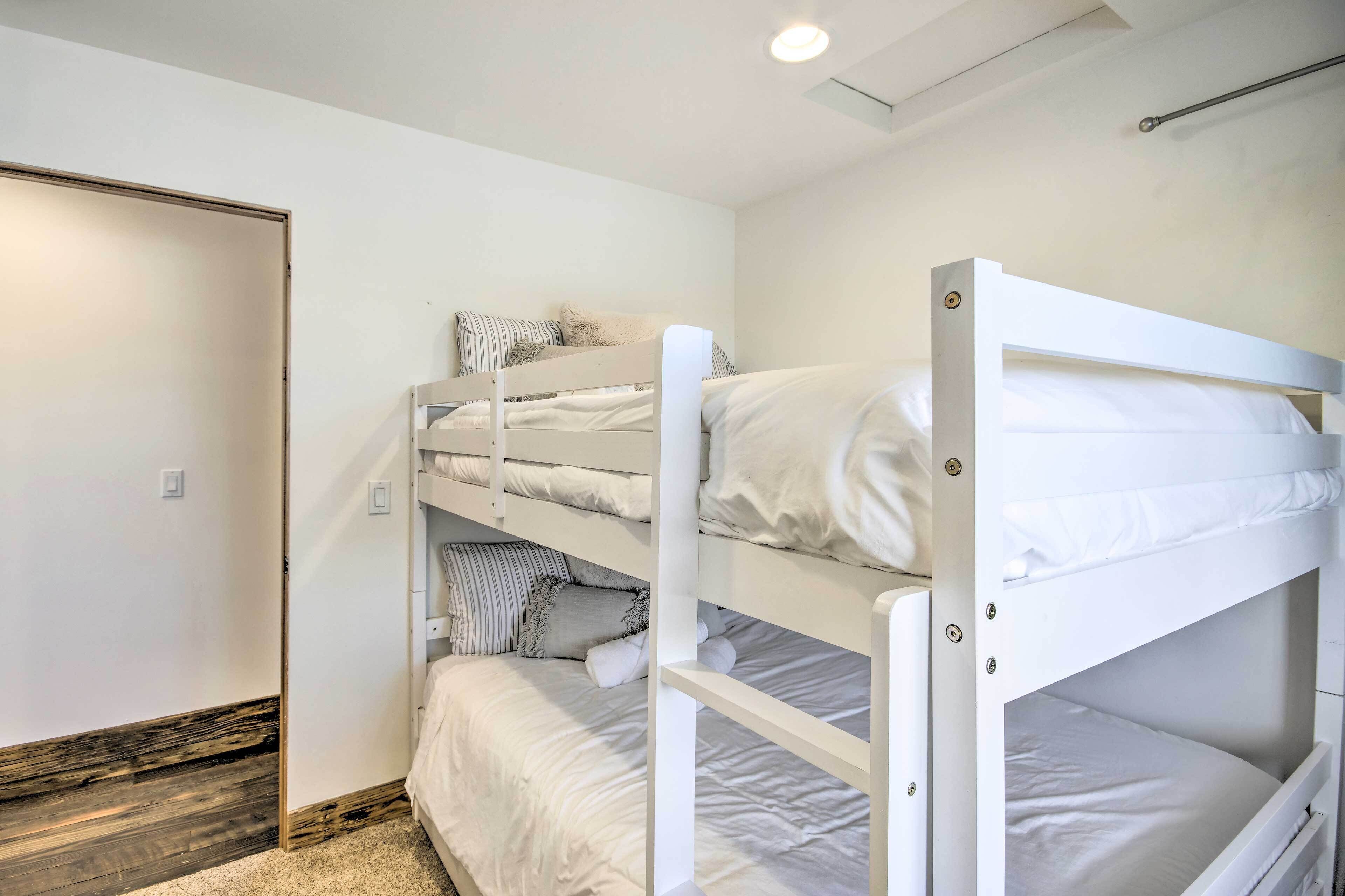 Dormitorio con literas, ropa de cama blanca y suelo de madera.