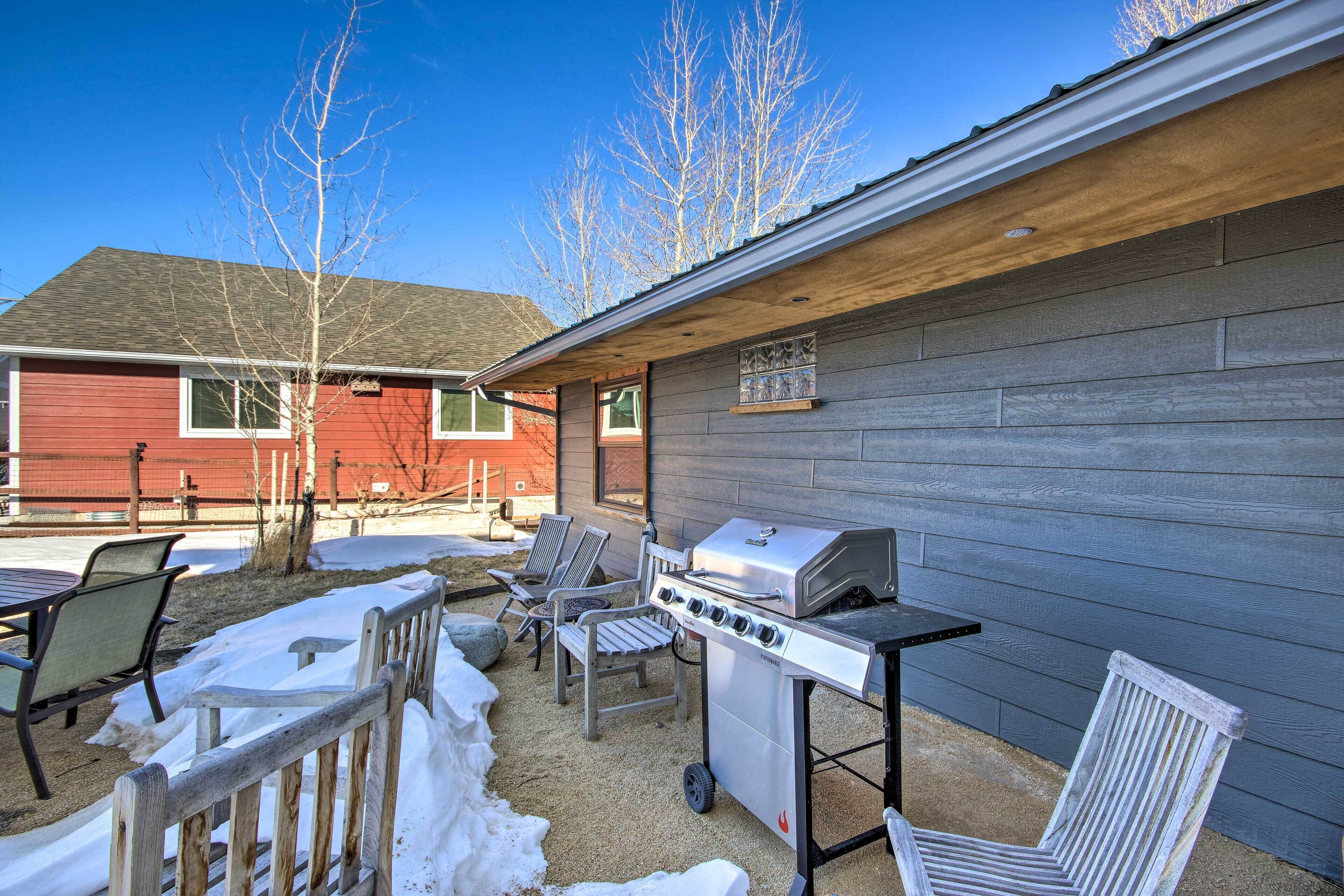 An outdoor patio with a grill, chairs, and a table.