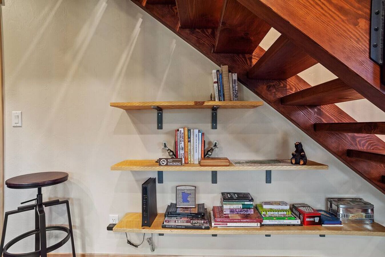 Una escalera con barandillas de madera y una estantería con varios libros y objetos decorativos.