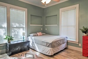 A bedroom with a bed, a dresser, a nightstand, and a window with blinds. - Historic Moss Point House w/ Loft - 6 Mi to Beach! (Moss Point)