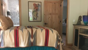 Una camera da letto con un letto grande, un tappeto in pelle di vacca, una porta in legno e un quadro appeso al muro.