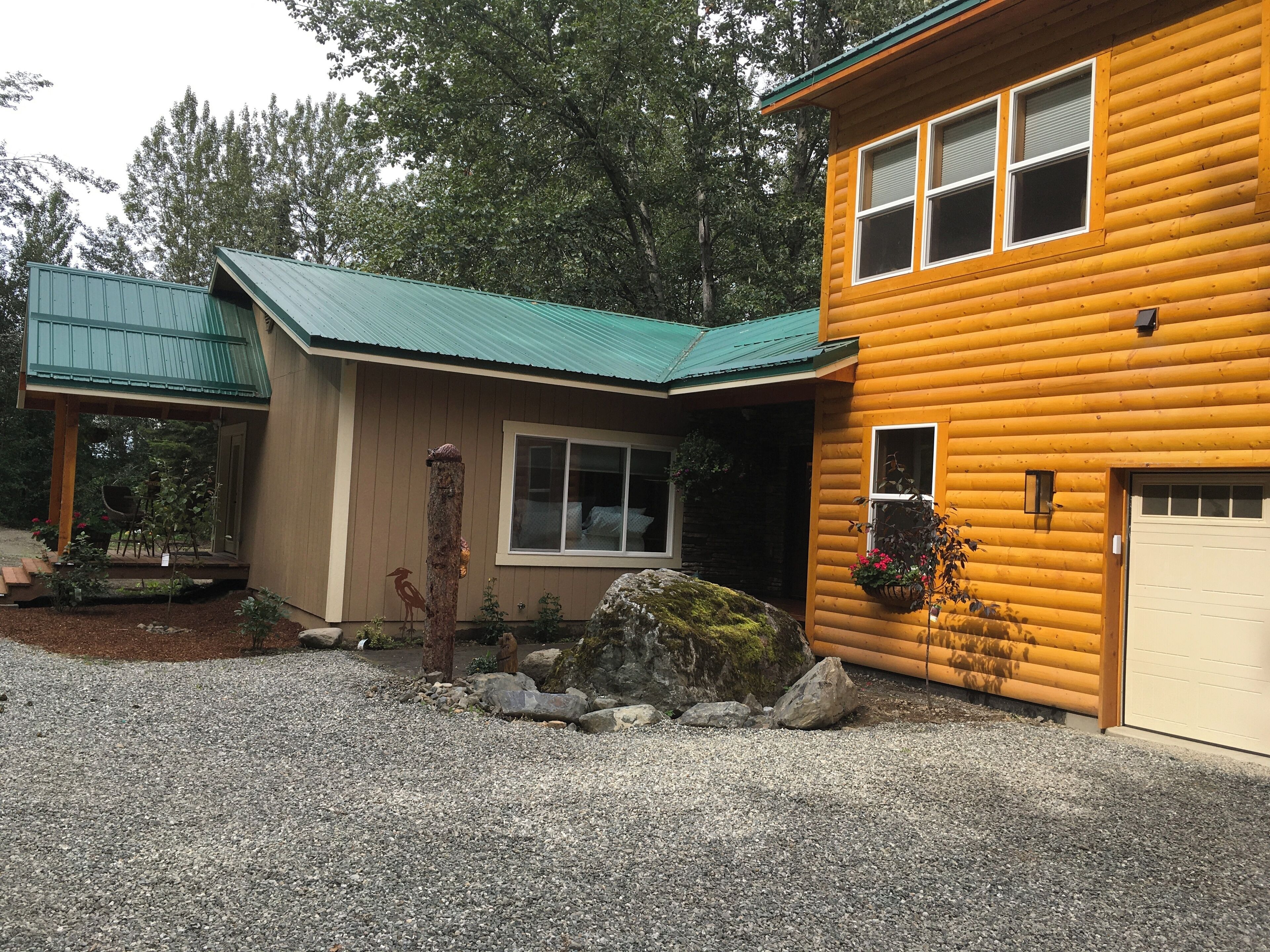 Une cabane en rondins à deux étages, dotée d’un toit végétalisé et d’une allée en gravier.