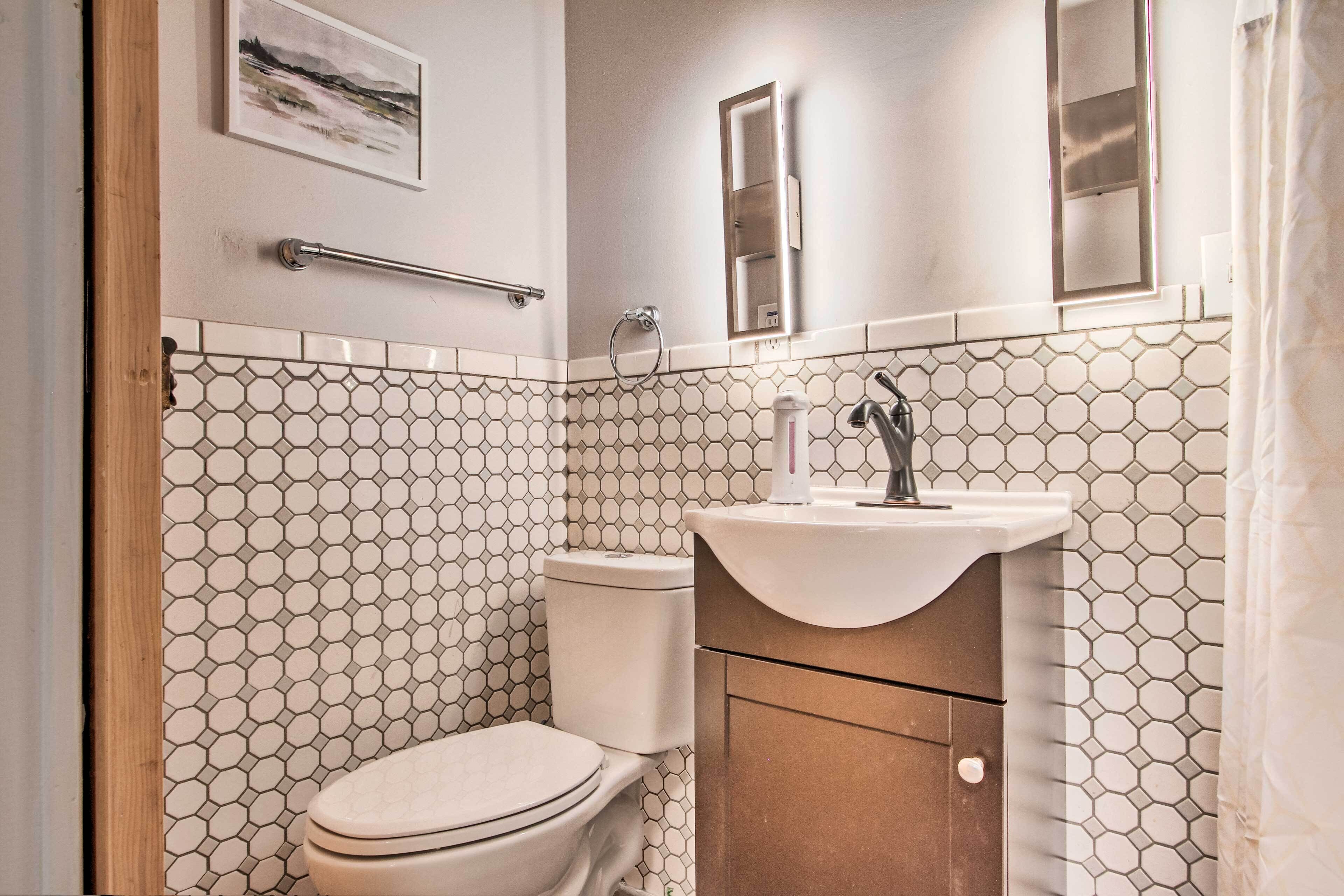 A bathroom with a toilet, sink, and mirror.