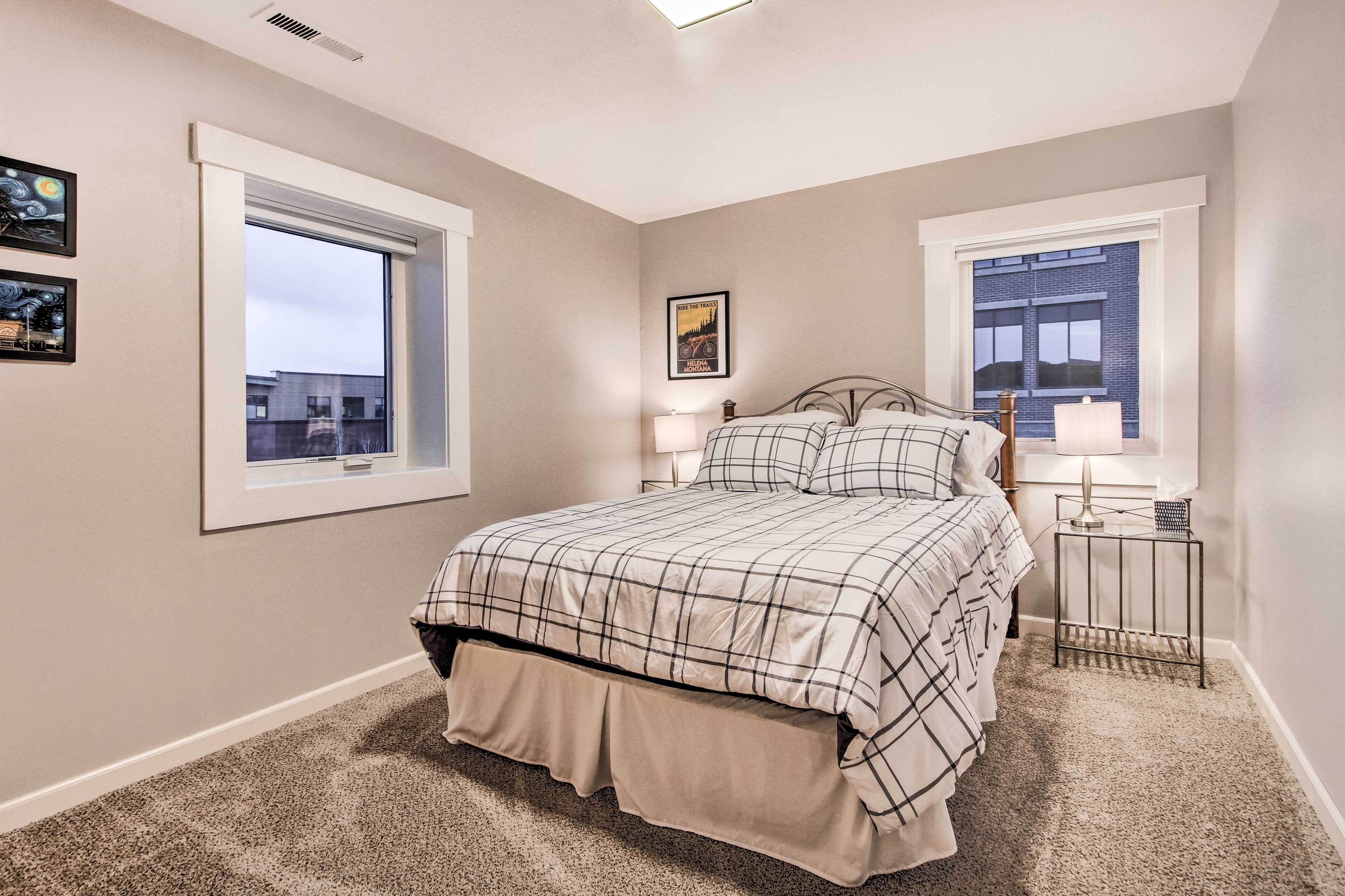A bedroom with a bed, two bedside tables, a window, and a picture on the wall.