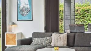 Een moderne woonkamer met een grijze bank, een klein wit tafeltje en een ingelijste foto aan de muur.