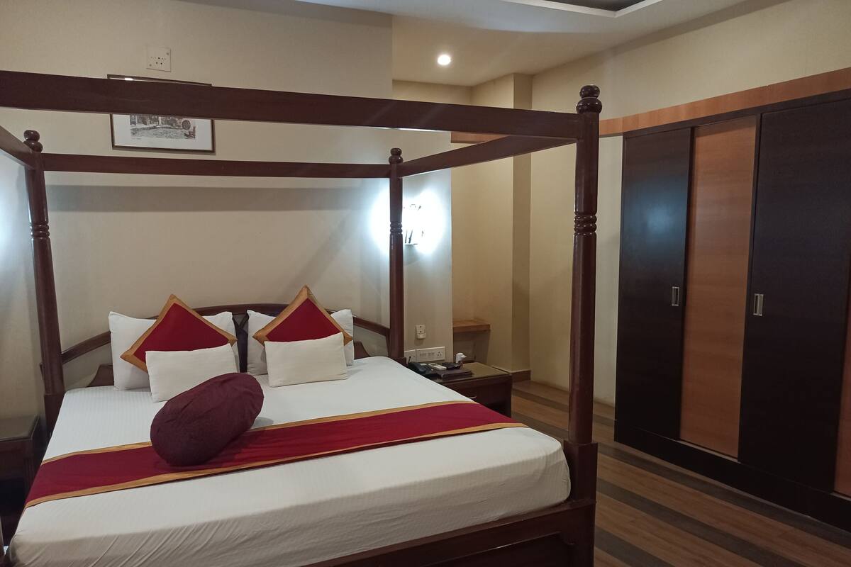 A four-poster bed with a red and white bedspread, a wooden headboard, and a red throw blanket.