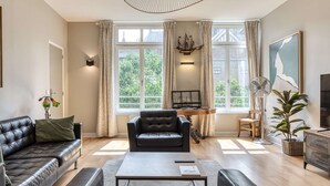 En moderne stue med en lædersofa, et sofabord og et skrivebord med en skibsmodel.