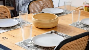 Et spisebord dækket med tallerkener, skåle og glas, med tallet '03' synligt på bordet.