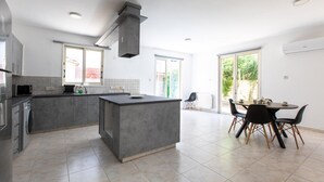 Una cucina moderna con isola centrale, elettrodomestici integrati e zona pranzo con tavolo e sedie.
