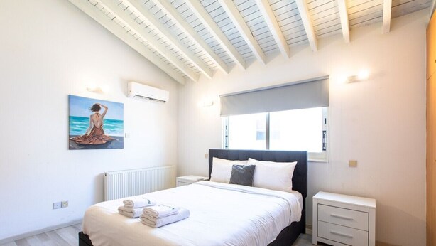 Una camera da letto con un letto, un comodino, una finestra, un termosifone e un quadro appeso al muro.