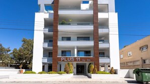 A multi-story building with a sign reading "PLUS 11 by GC". - Kmeidos 1-Bedroom Apartment & Balcony in Larnaca (Cyprus - Larnaca)