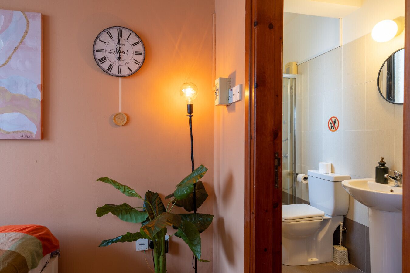 Ein Badezimmer mit Toilette, Waschbecken und einer Wanduhr.