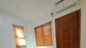 A small bedroom with two single beds, a wooden door, and a window with blinds.